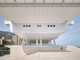 Mareterra, Renzo Piano Building Workshop, Monaco, 2024 — underside of elevated building volume on pilotis with Monaco cityscape and two figures 